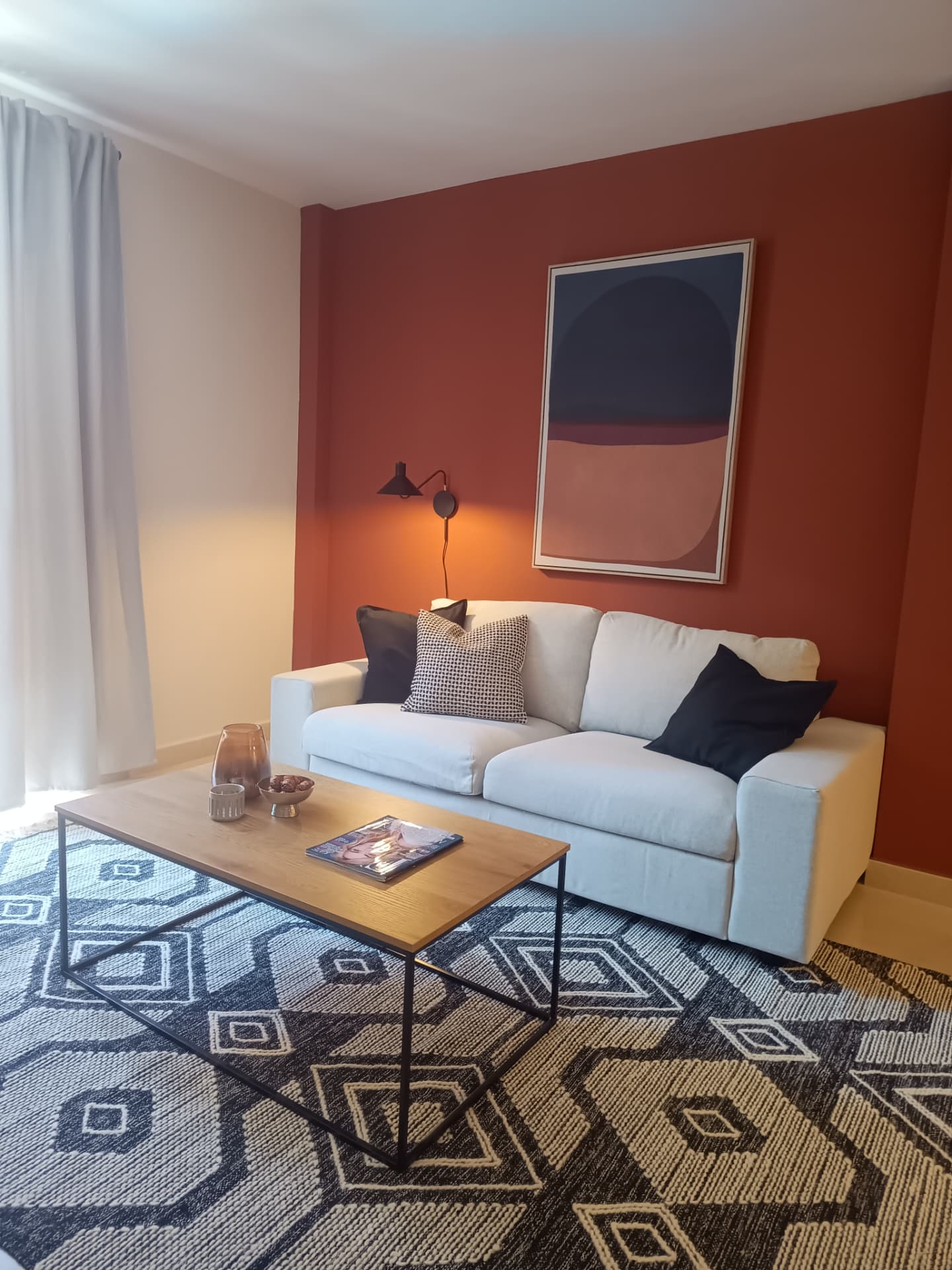 Salón con sofá blanco, pared terracota, lámina abstracta y alfombra étnica