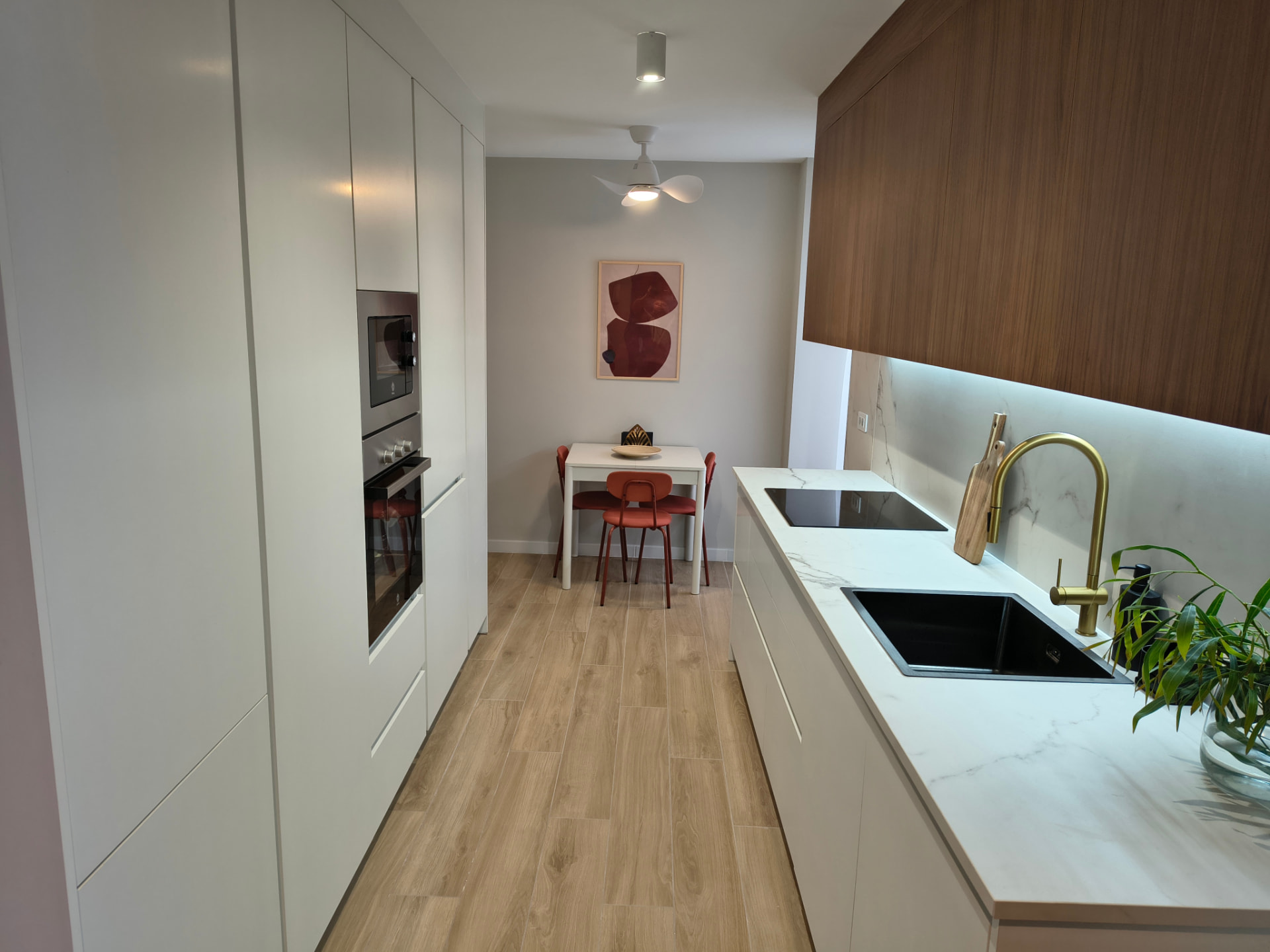 Cocina blanca con frentes de madera y sillas rojas