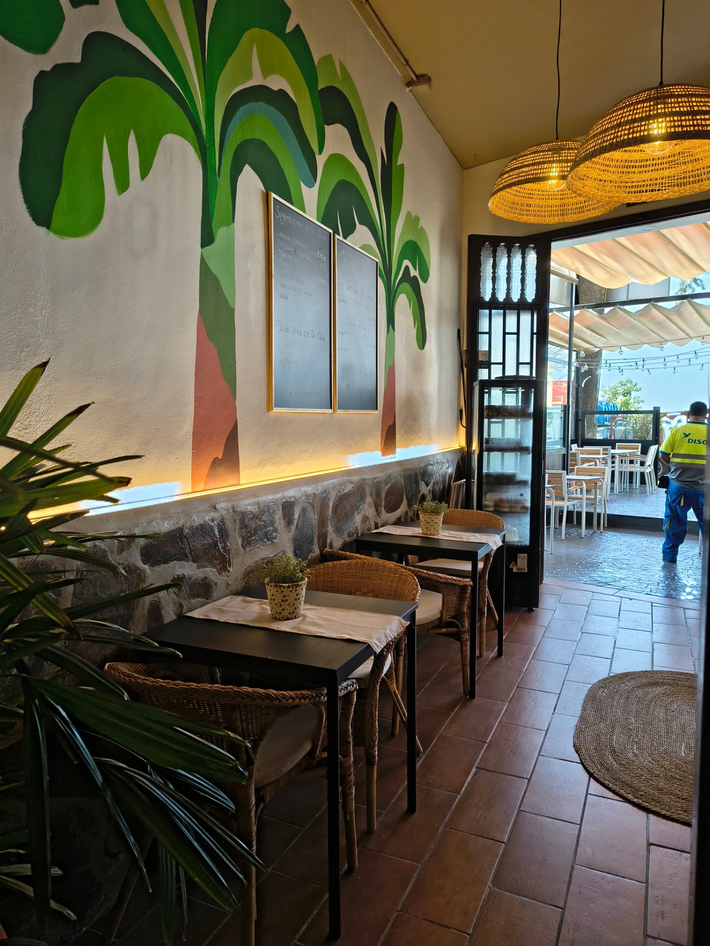 Sala de restaurante con mural pintado a mano, zócalo de piedra y lámparas de fibra