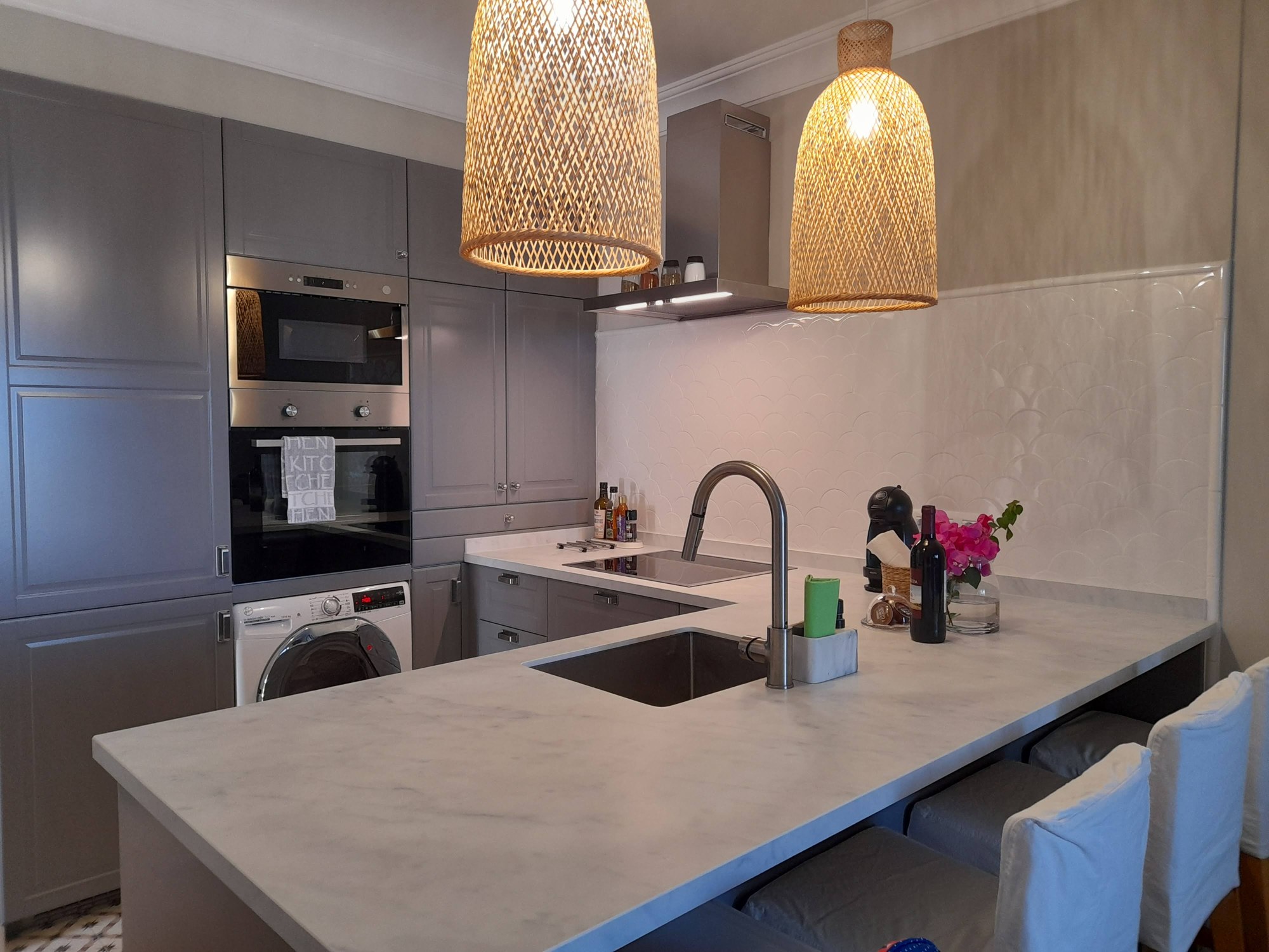 Cocina en gris con península, encimera clara y lámparas de fibra natural