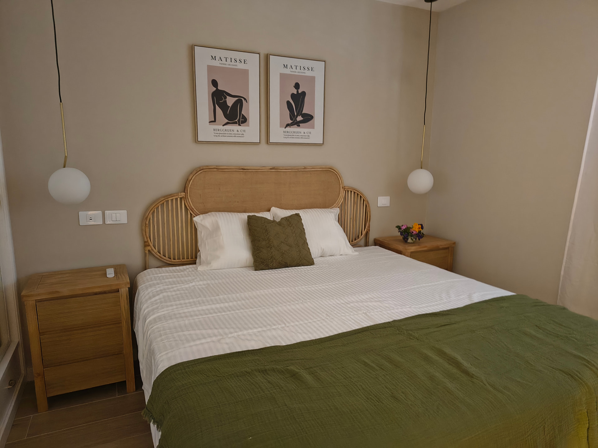 Dormitorio con cabecero de ratán, mesillas de madera y colcha verde oliva
