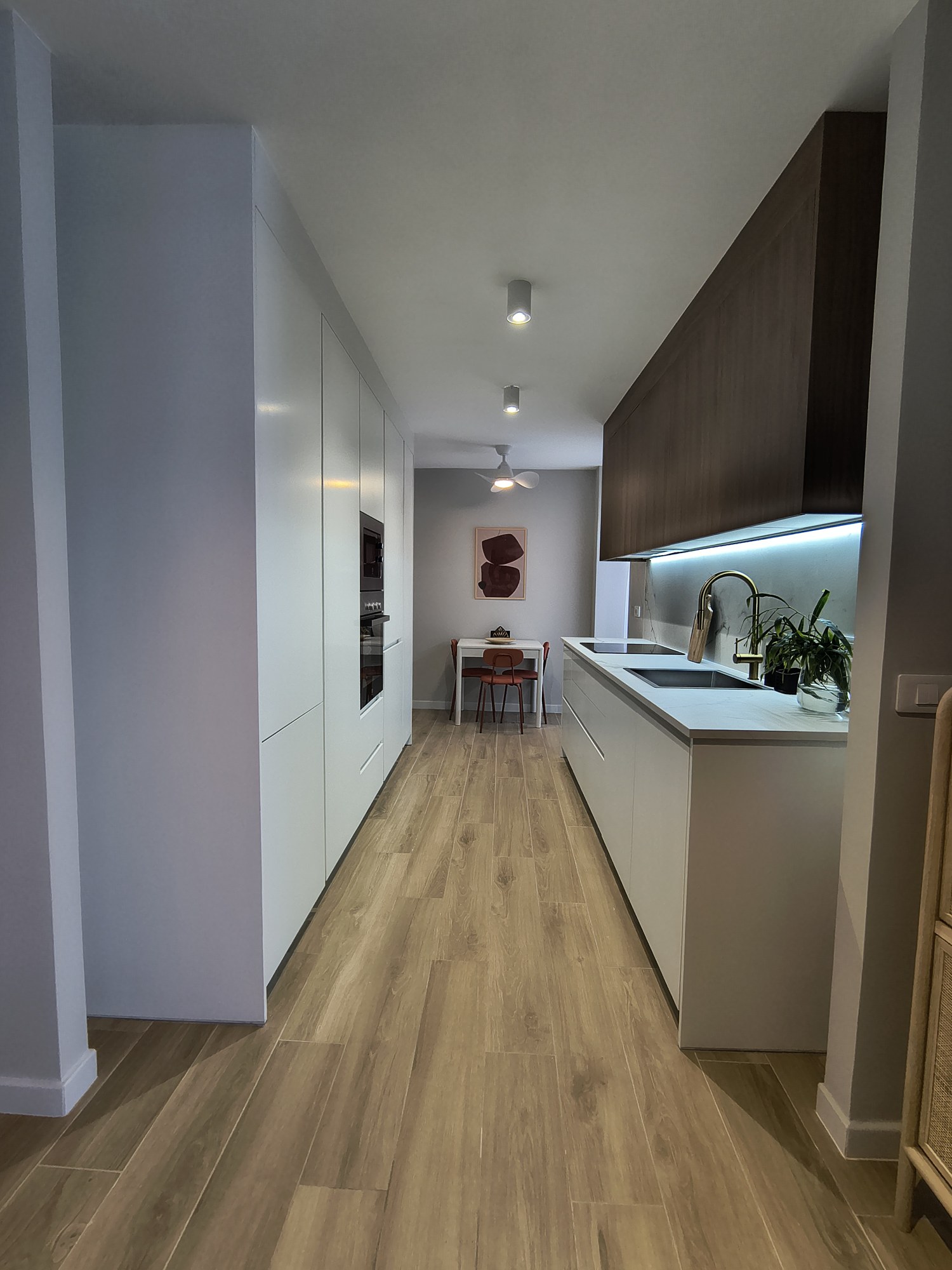 Cocina lineal con frentes blancos y revestimiento de madera