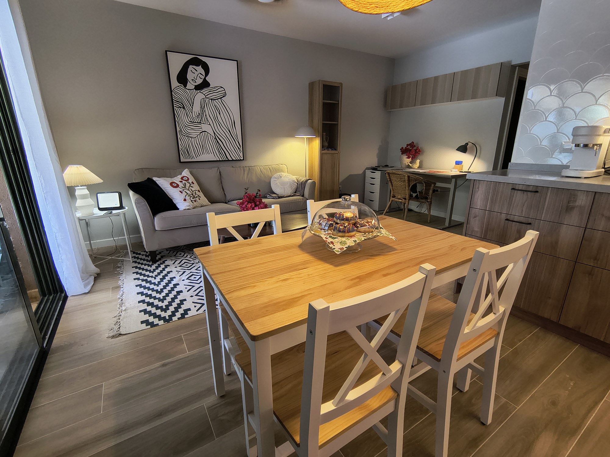 Salón comedor con mesa de madera, sofá gris y alfombra geométrica