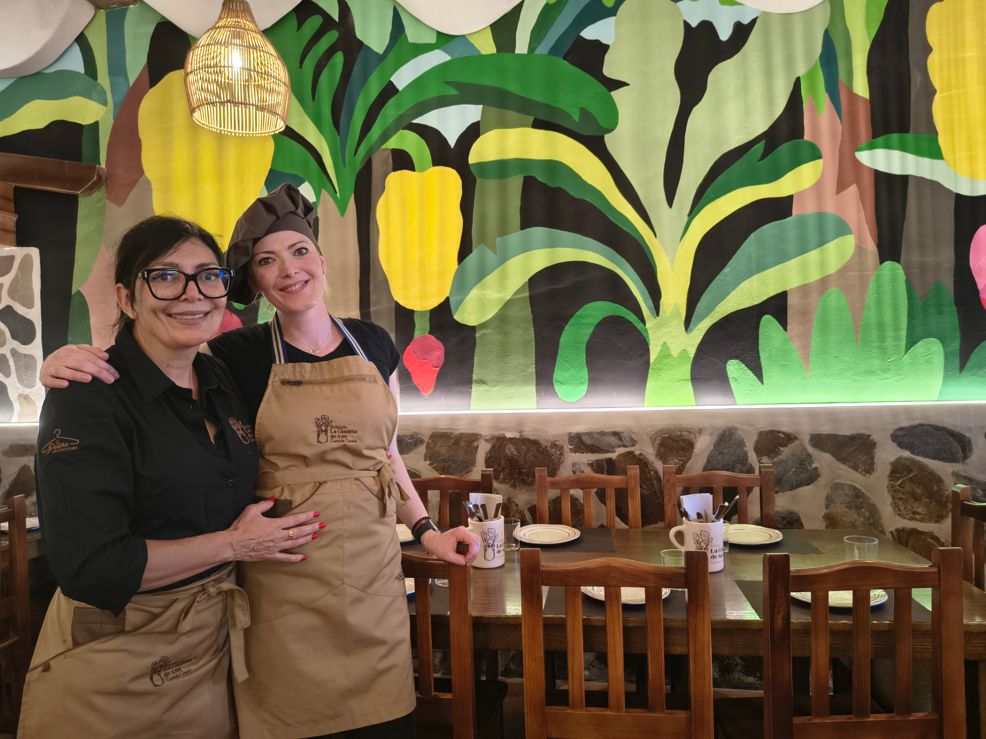 Interior de restaurante con gran mural tropical y mobiliario de madera